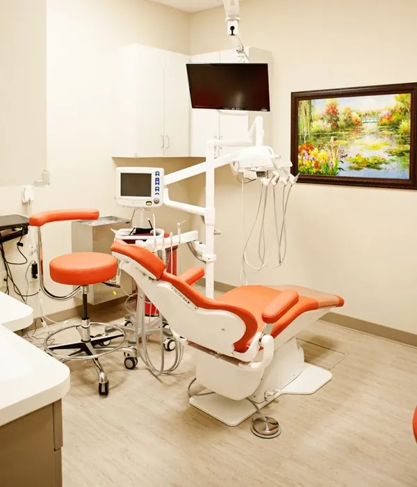 A Northshore Dental treatment room with an orange dental chair and a painting on the wall.